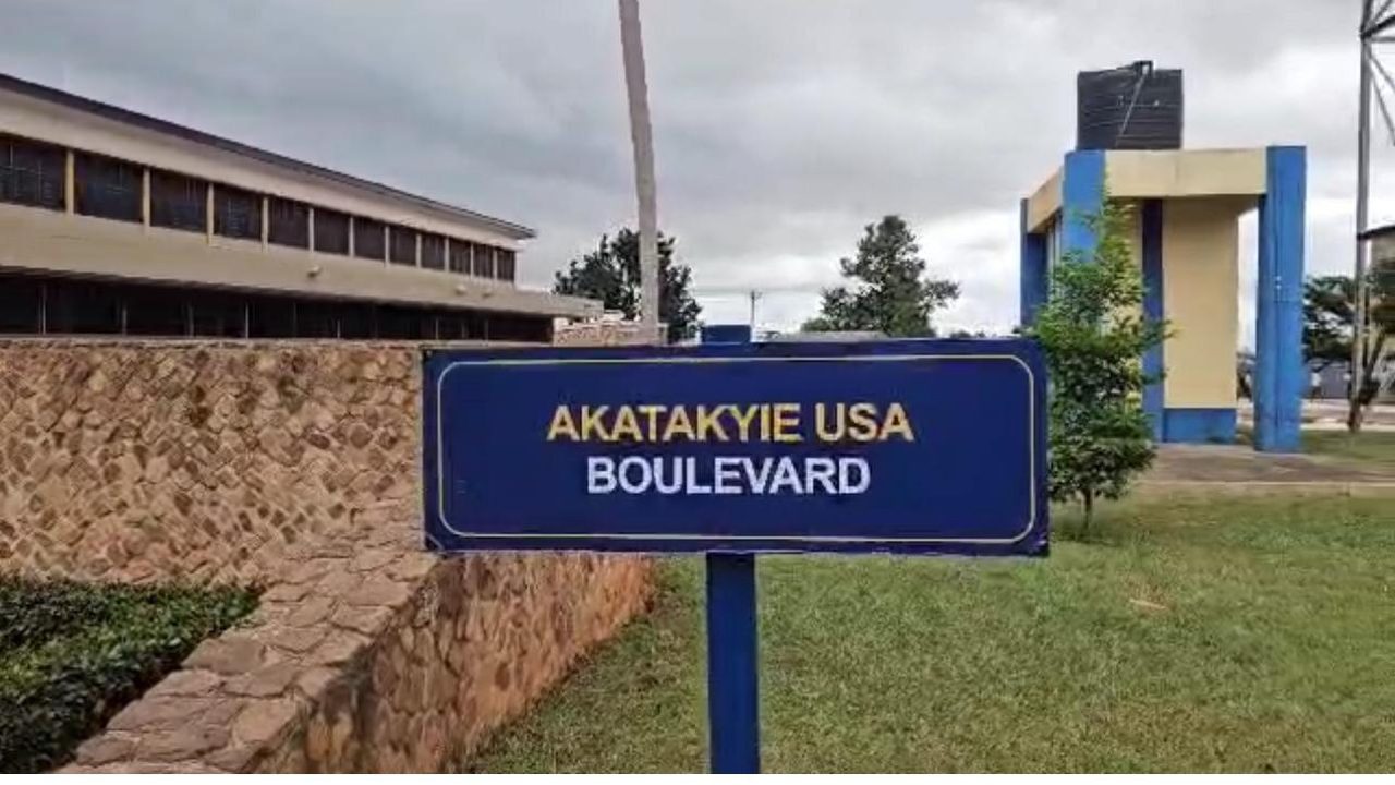 A blue and gold street sign reading Akatakyie USA Boulevard on the school campus