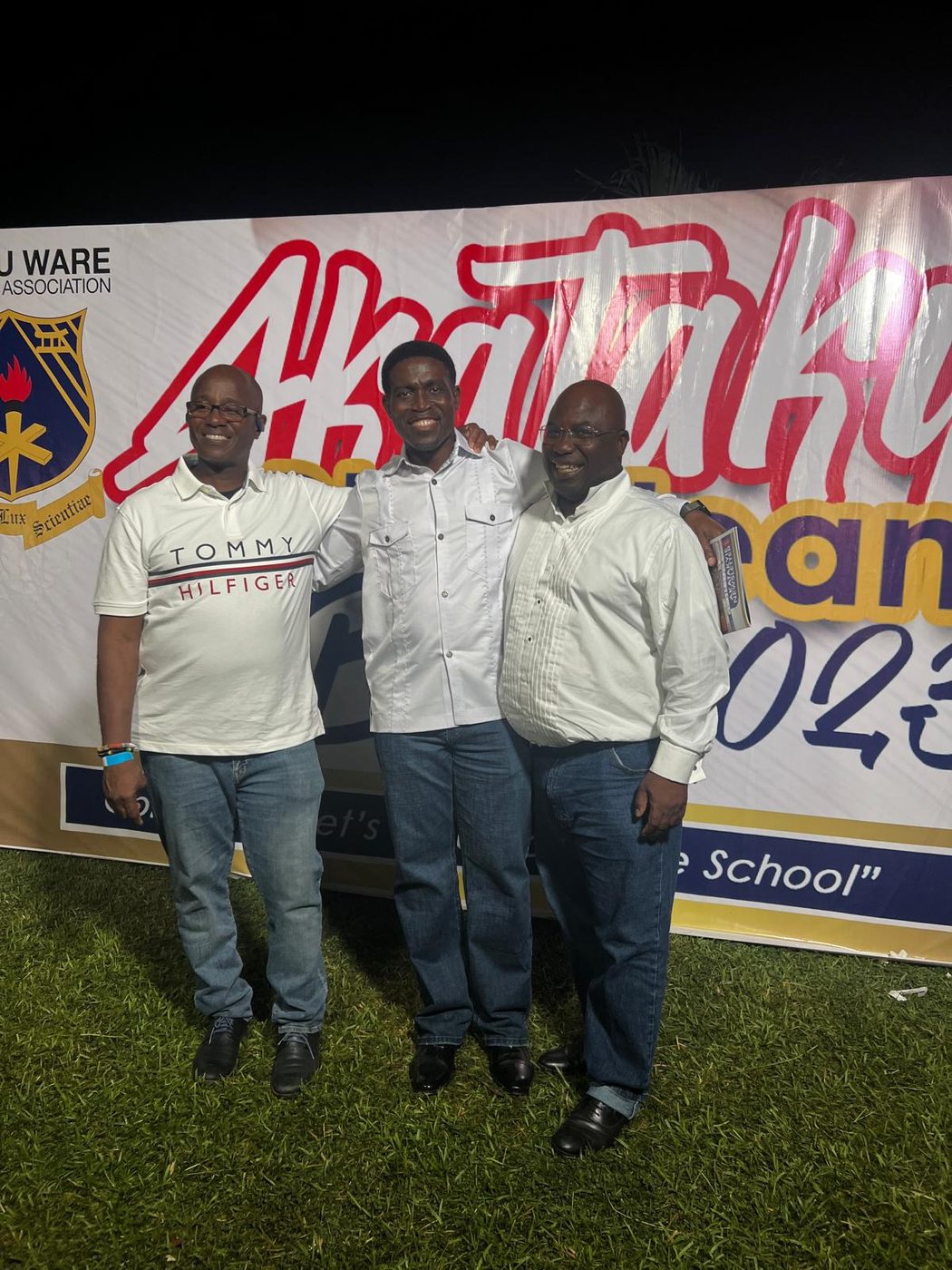 Three Akatakyie members in front of a banner for the Global Akatakyie Ball in Kumasi